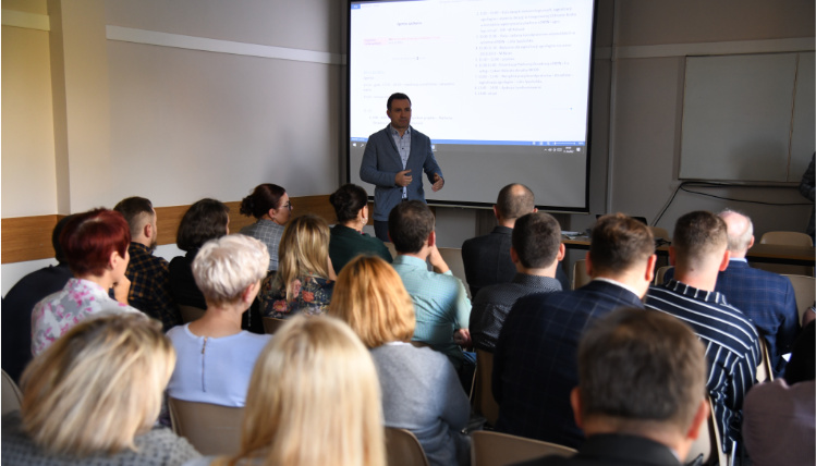 Na konferencji zgromadziło się kilkadziesiąt osób Wnętrze sali wykładowej. Dyrektor Jacek Sommerfeld przemawia przed grupą ludzi siedzących na krzesłach.