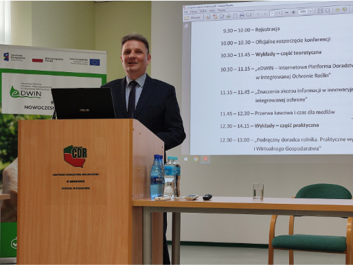 Oficjalnego otwarcia konferencji dokonał Mariusz Tatka, dyrektor Centrum Doradztwa Rolniczego w Brwinowie, oddział w Poznaniu Wnętrze pomieszczenia. Mariusz Tatka, mężczyzna w średnim wieku, stoi w czarnej marynarce przed rzutnikiem. Przed nim, na mównicy jest postawiony laptop.. W tle widać rollup promujący platformę eDWIN.